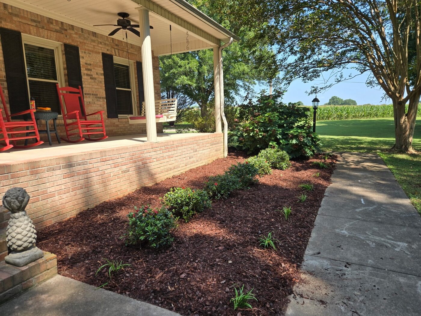 Freshly planted and mulched porch landscape completed by Bates Lawn Care